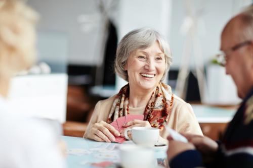 Old woman smiling at old man while having lunch together
