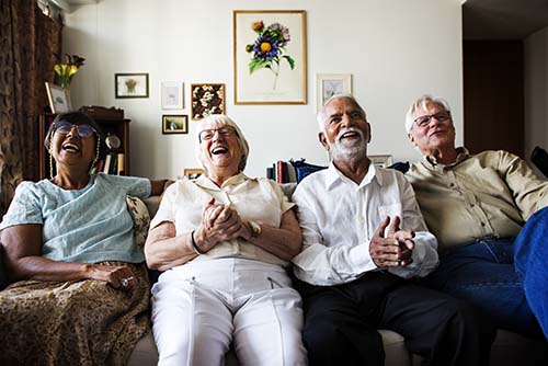 Senior citizens watching TV and laughing together