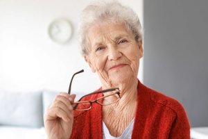 Old woman is taking off her glasses