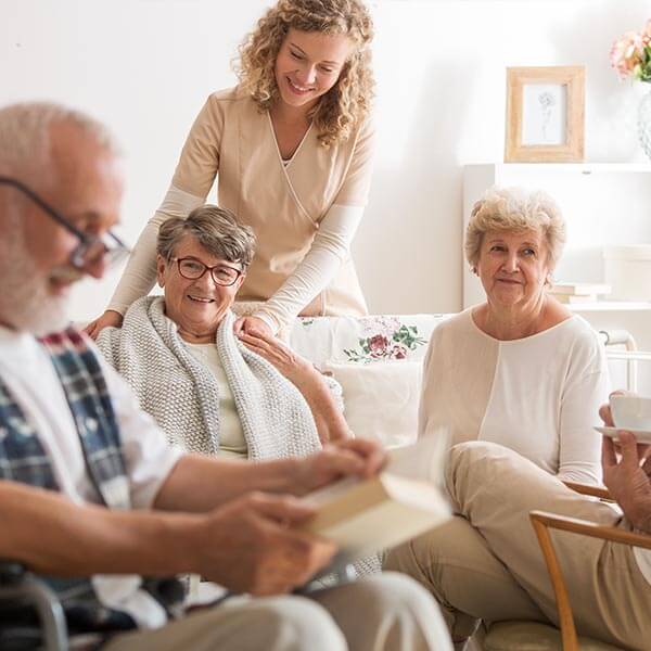 Senior citizens gather in the living room with their caregiver