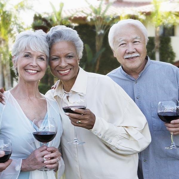 Senior citizens take a picture together while lifting a glass of drink