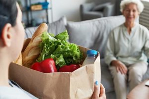 Caregiver gives a bag full of fruit to an old woman