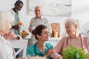 Caregiver helps happy senior citizens prepare their lunch