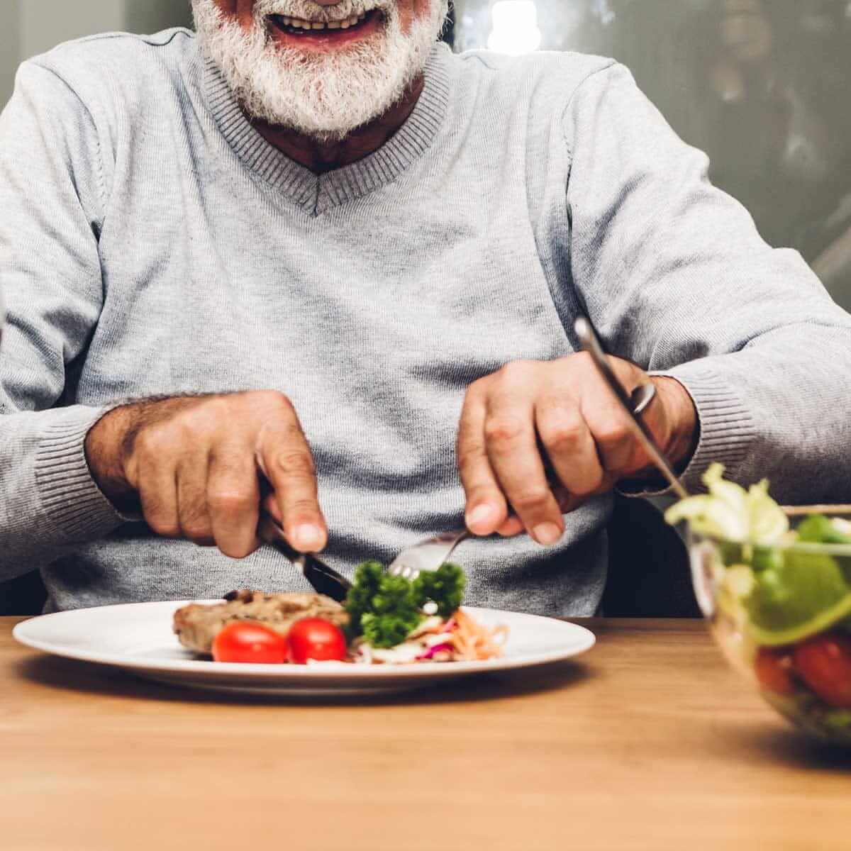 Old man eating chef-prepared meals on the table