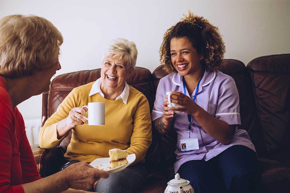 Senior citizens and her caregiver enjoying coffee together