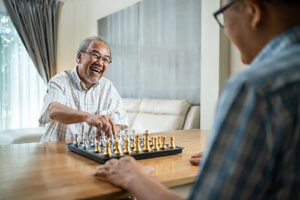 happy old man playing chess with his friend
