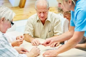 Caregiver help senior citizens playing puzzle game