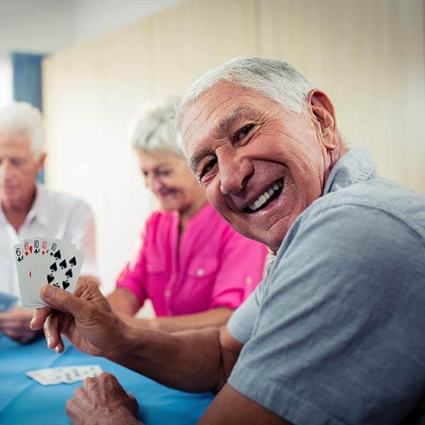 Happy old man enjoying card game with other senior citizens