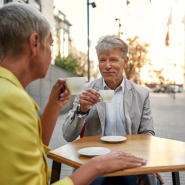 Old man drinking tea outdoors with his friend