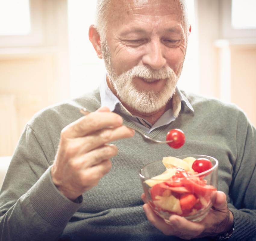 Old man eating grapes and apple slices