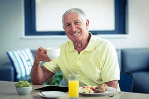 Old man carrying a cup of coffee and smiling