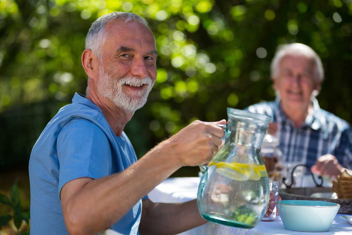 Old man with his friend from senior living enjoying outdoor dining
