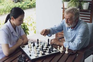 Caregiver playing chess with old man