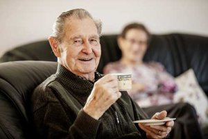 Old man drinking coffee and smiling