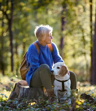 a-senior-woman-with-dog-on-a-walk-outdoors-in-forest