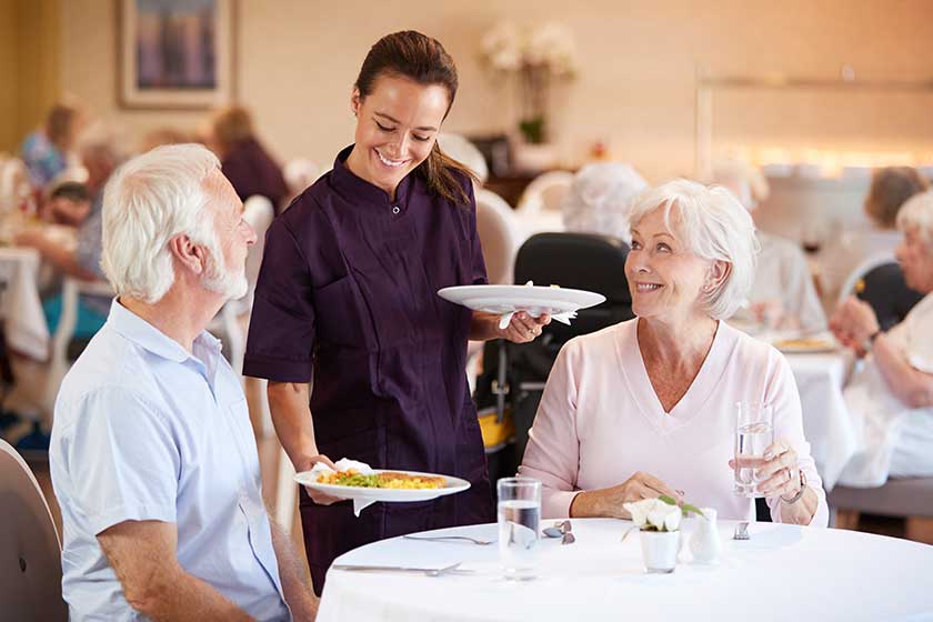 Senior Couple Being Served With Meal