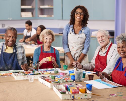 Portrait Of Retired Seniors Attending Art Class In Community Centre With Teacher