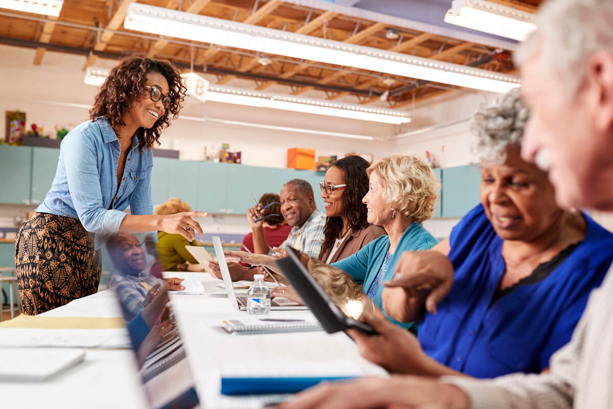 Group Of Retired Seniors Attending IT Class In Community Centre With Teacher